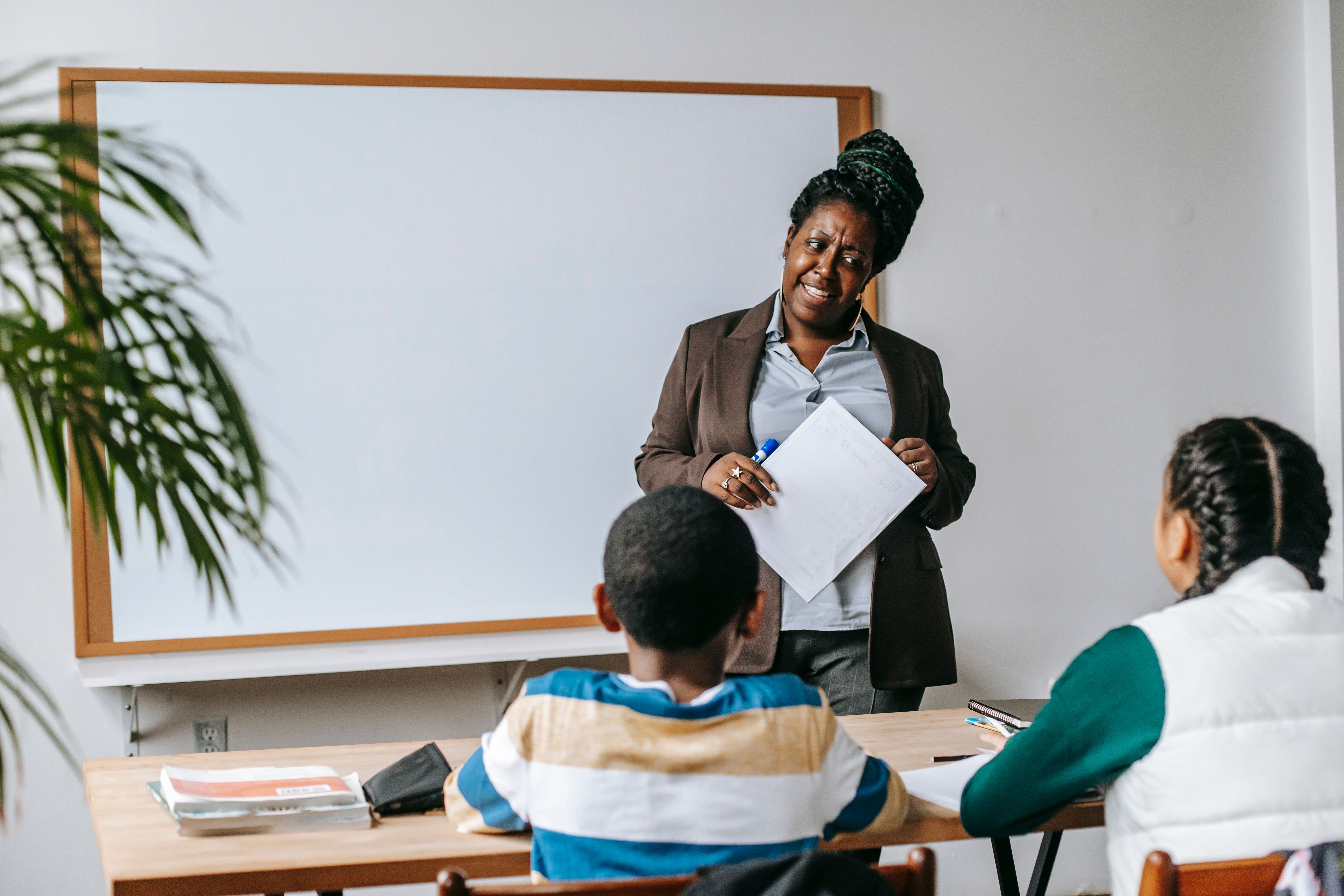 Professora sorrindo com seus alunos em sala de aula